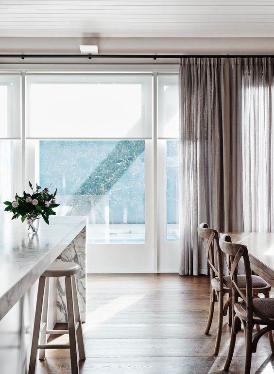 white blinds and taupe flowy curtains add privacy to the space and make the windows look cooler while blocking excessive sunshine
