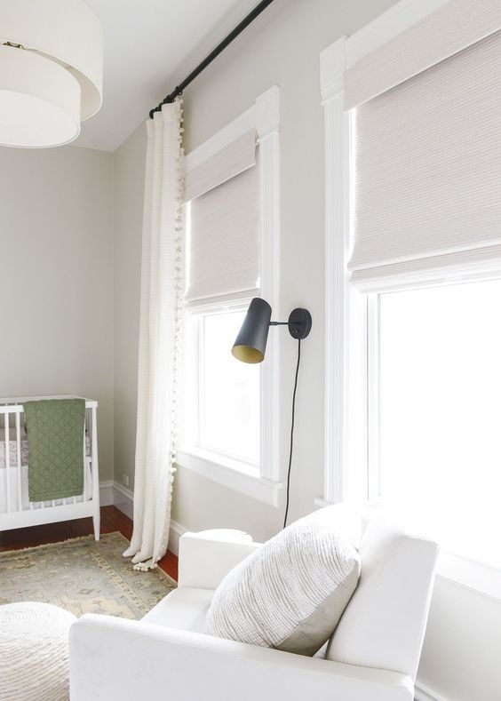 white textural blinds and creamy pompom curtains add coziness to the kid room and block out the excessive sunshine easily