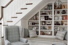 06 a lovely neutral reading nook with built-in shelves udner the stairs, a comfy daybed plus an additional wingback chair