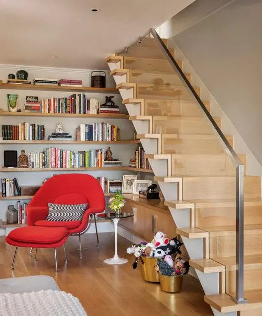 a reading nook with lots of stained wall-mounted shelves, cabinets and a bold red mid-century modern chair is ultimate