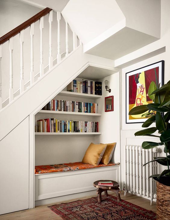 a small and cozy reading nook with built-in bookshelves, a daybed with bright bedding and a bold artwork