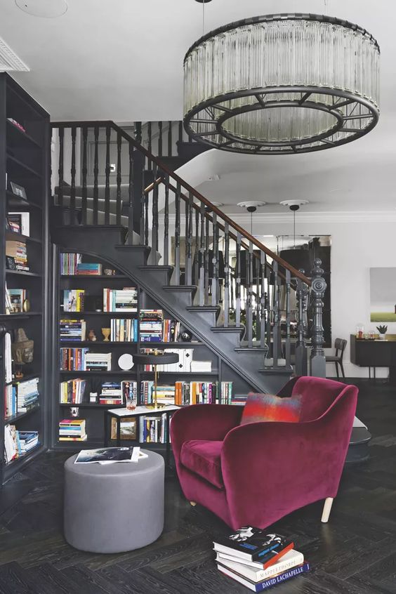 a sophisticated moody space in black, with a staircase featuring a bookcase, a beautiful purple chair for reading here