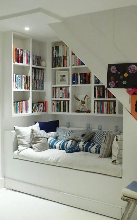 a welcoming white reading nook with built in bookshelves and a couch with storage is a very cozy space to curl here