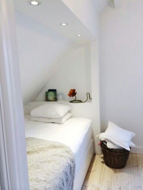 an awkward attic nook with a bed for one, some decor and built-in lights plus a curtain to make the space more private