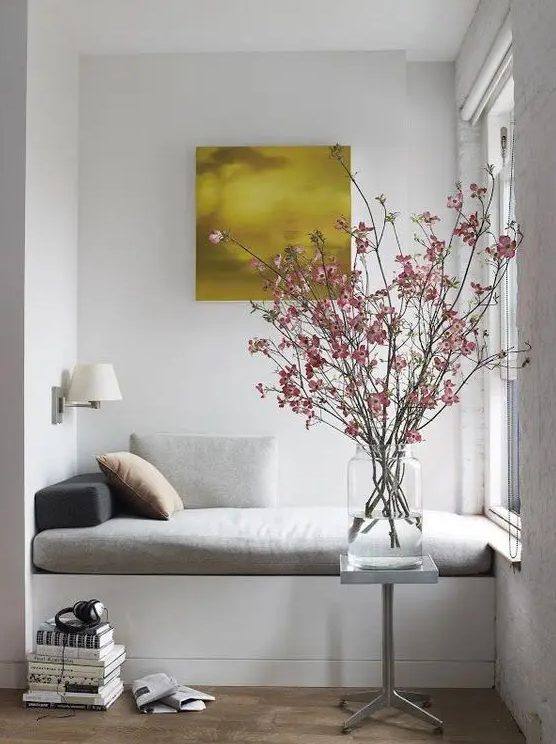 a small nook by the window is taken by a daybed with pillows and upholstery, great for reading and having a nap