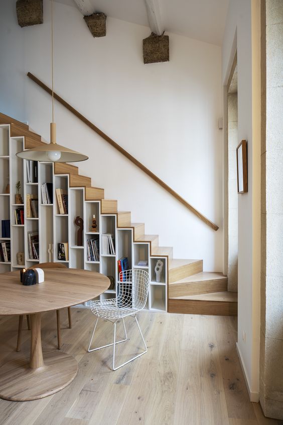 a contemporary light stained staircase with shelves built in, both for books and other items for displaying