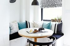 21 a contrasting eating space with a built-in corner sofa, lots of printed pillows, a round table and a comfortable black chair
