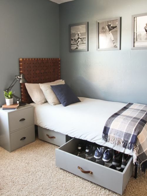 a stylish grey bedroom with a bed with a woven headboard and storage drawers under the bed, a matching nightstand and a gallery wall