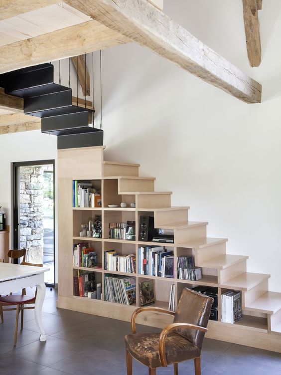 a contemporary space with a light-stained and dark staircase with lots of built-in bookshelves for effective storage and a stylish look