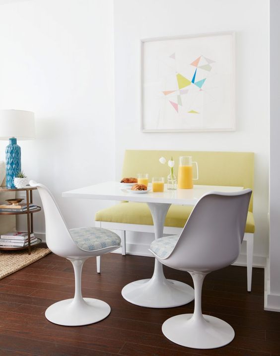 a modern and bright breakfast nook with a mustard loveseat, a white table and catchy white chairs with upholstery
