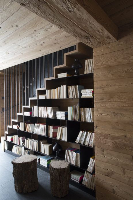 a stained staircase with lots of bookshelves under it is a cool idea for any space, here it's integrated into a chalet home