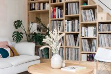 30 a stylish mid-century modern space with a bookcase staricase, a sofa, a round table and a comfy chair is very chic and practical