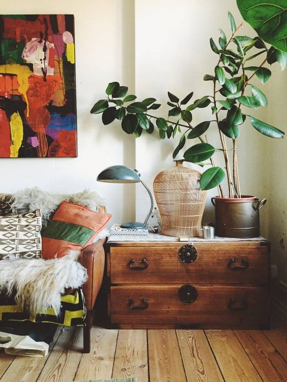 a cozy and cool nook takedn by a large vintage sideboard, with a potted plant, a cage and a lamp is a lovely idea