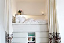 37 a tall bed built of several layers of drawers and open storage ocmpartments is a cozy and functional unit