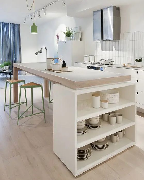 a Nordic kitchen with white cabinets and butcherblock countertops, a large kitchen island that is a table and an open storage unit for tableware