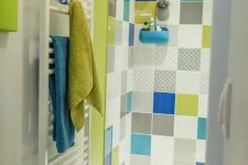 a bright bathroom in white accented with a neon green shower and multi-color tiles, with neon green and blue textiles