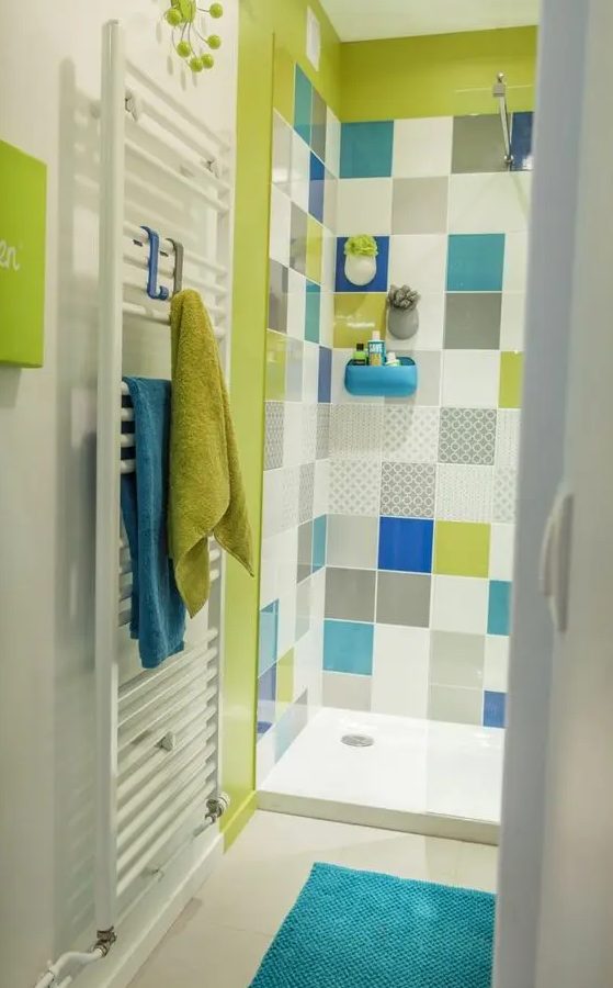 a bright bathroom in white accented with a neon green shower and multi color tiles, with neon green and blue textiles