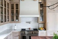a catchy and welcoming kitchen with a whitewashed ceiling and cabinets, with a reclaimed wood floor and a kitchen island with a reddish countertop