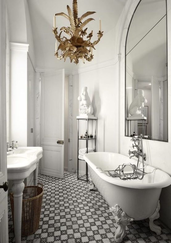 a chic vintage-inspired French style bathroom with a tiled floor, a gorgeous whimsy chandelier, a free-standing sink and a statement mirror