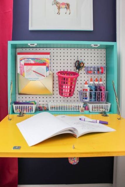 a colorful Murphy desk with a turquoise base and a yellow door, with a pegboard for smart storage inside is ideal for a kid's room