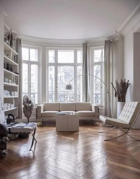 a contemporary Parisian living room with all whites and a hardwood parquet floor to soften the space