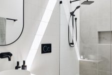 a contemporary bathroom clad with white skinny tiles, with a neutral vanity, a walk-in shower with black fixtures and a niche for storage