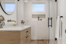 a contemporary bathroom with white tiles, a wooden floor, a floating vanity, black fixtures and a glass door in the shower