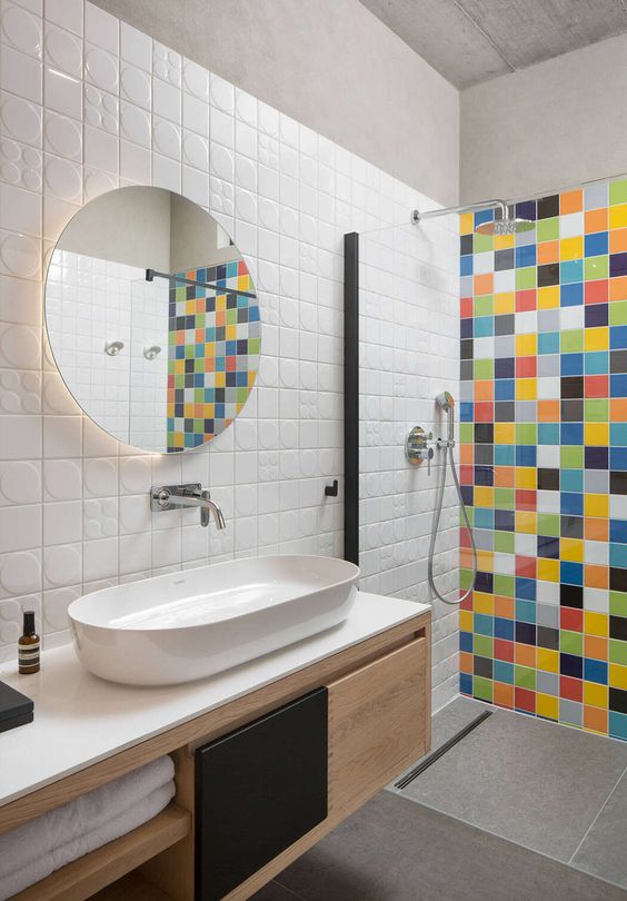 a contemporary space with white tiles, large scale grey tiles and a bold multi color accent in the shower space