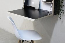 a cool small working space with a black Murphy desk with a potted plant and all the gadgets, a simple white chair