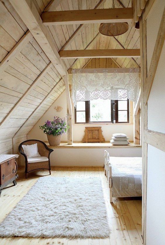 a cozy cabin bedroom with blonde wood on the walls, ceiling and floor, with vintage cottage furniture, blooms in a basket and a lace curtain