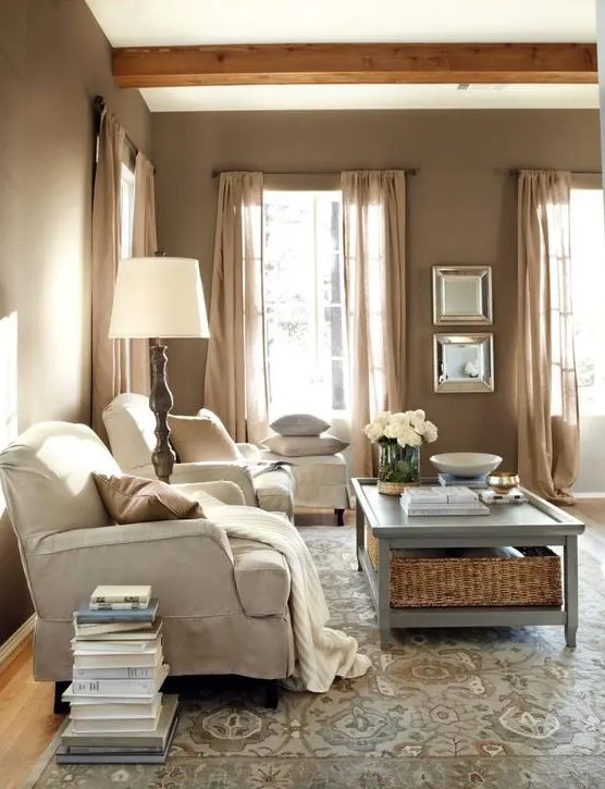a cozy farmhouse living room design with taupe walls, neutral vintage furniture, a vintage floor lamp, a blue coffee table with storage