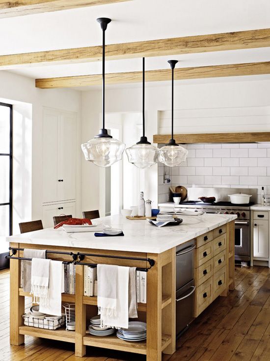 a cozy small kitchen with vintage cabinets, wooden beams on the ceiling, a large stained kitchen island with drawers and open shelves
