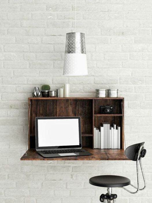 a dark-stained Murphy desk with books and some vintage decor, a pendant lamp and a black chair