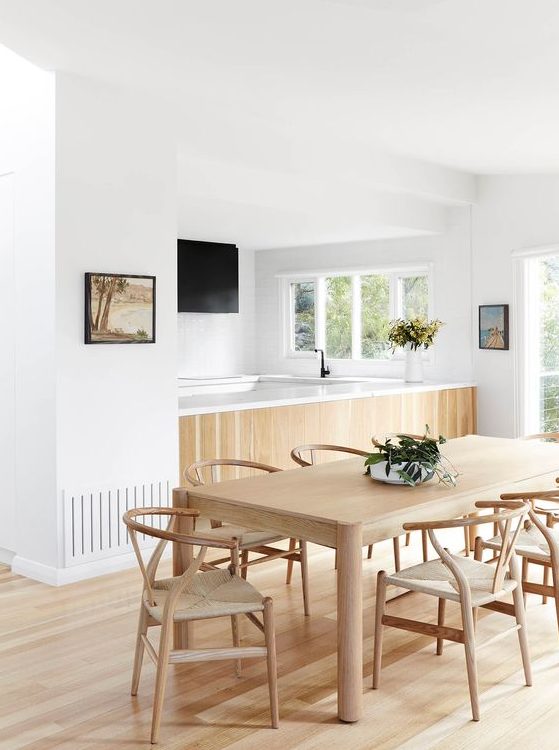 a dining zone with a blonde wood floor, table and chairs plus a kitchen island clad with the same wood