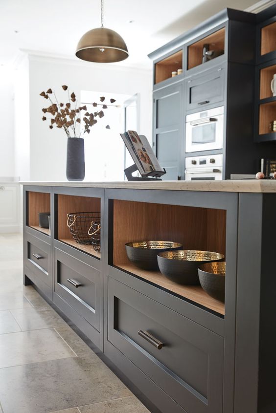 a graphite grey shaker style kitchen with stone countertops and an oversized kitchen island with drawers and niches for storage