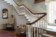 a historic house with light-stained floors, dark-stained railing, white paneling, lots of refined vintage artworks