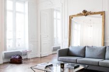 a light-filled and airy French chic living room with a grey sofa, a leather daybed and a table with geometric legs