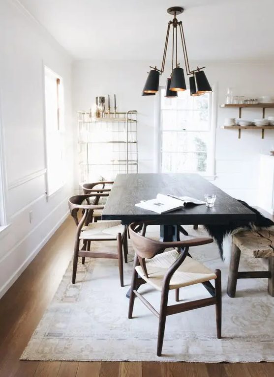 a light-filled dining space with a very dark-stained table that makes a statement, rich-stained chairs and a light-stained floor, a black pendant lamp and open shelves