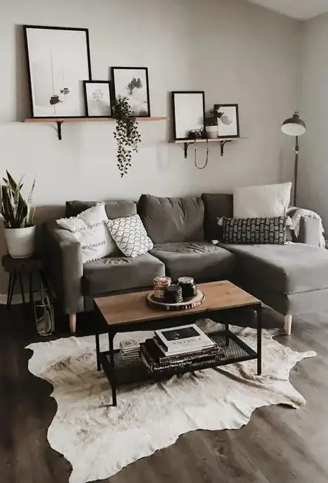 a light grey living room with a taupe sectional, a mini gallery wall, potted plants, an animal skin rug and a small coffee table