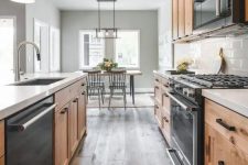 a modern farmhouse kitchen with light-stained cabinets, black built-in appliances and a dark reclaimed wood floor is amazing