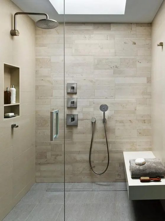 a modern walk-in shower clad with wood-like tiles, with a tiled floor, a built-in bench and niches for storage plus a skylight
