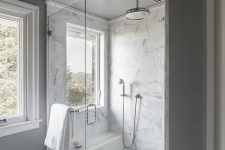 a neutral bathroom with grey walls, a white marble tile floor, a white marble shower space and penny tiles on the floor