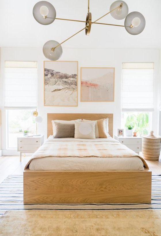 a neutral bedroom with a blonde wood bed, white nightstands, printed textiles and lovely artworks is pure chic