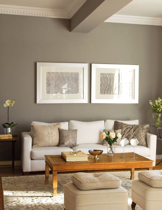 a pretty and cozy taupe living room with a white sofa and a low coffee table, a gallery wall and a taupe wooden beam