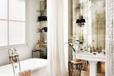a refined French chic bathroom with a mirror wall, a crystal chandelier, a tub, open shelves and a sink