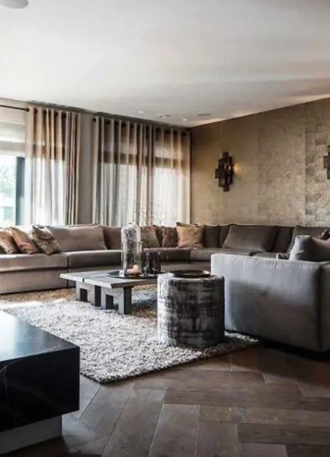 a refined living room with a metallic accent wall, a glazed wall, a taupe sofa, a grey rug, a simple low coffee table and a black marble one