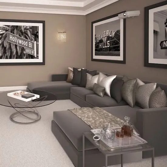a refined taupe living room with a grey sectional, an arrangement of metallic pillows, a black and white gallery wall, glass coffee tables