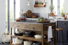 a small Scandi kitchen with black cabinets, white countertops, pendant lamps, vintage fixtures, a stained wood kitchen island with drawers and open shelves