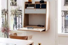 a small and elegant Murphy desk of light-stained wood, with built-in mini drawers for storage