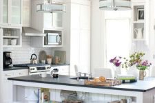 a small white kitchen with black countertops and a large kitchen island with large open shelves for storage is cool